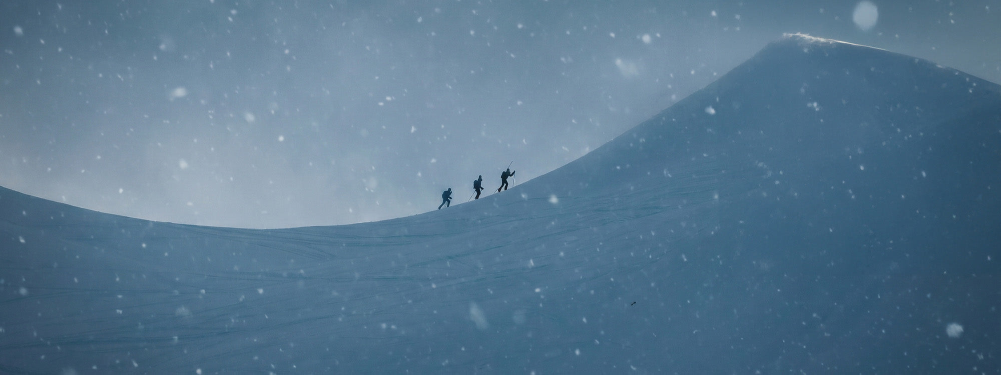 A dramatic snowy landscape with three ski mountaineers wearing SCARPA Alien 5.0 boots.