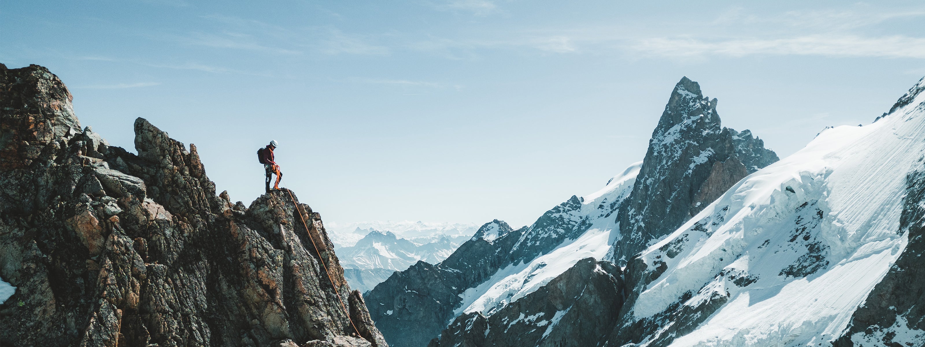 Alpinist standing on a rocky mountain peak with SCARPA's mountaineering boots
