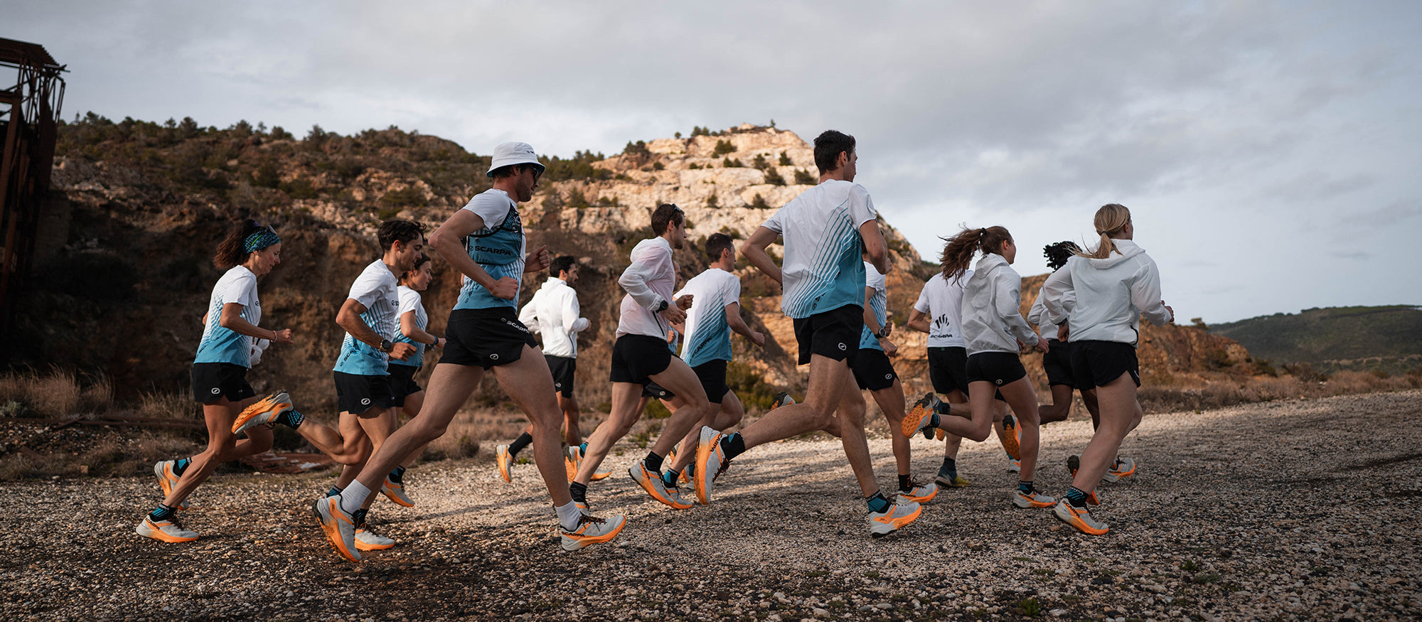 Runners on a dirt road with a mountainous landscape in the background with SCARPA's Spin Ultra 2 trail runnign shoes