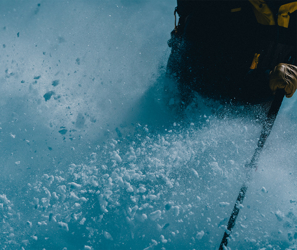 A close-up action shot of a skier carving through powder snow wearing SCARPA 4-Quattro PRO ski mountaineering boots.