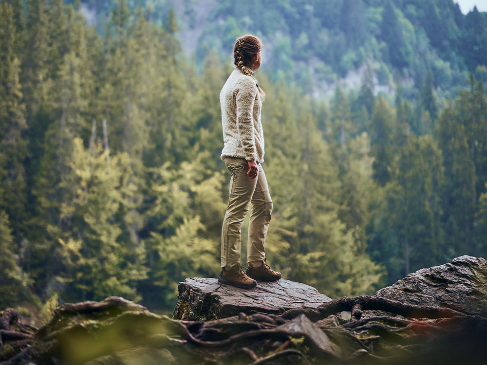 Hiker standing on a rocky outcrop in a forest wearing SCARPA's Rove Rock S GTX urban outdoor shoes.