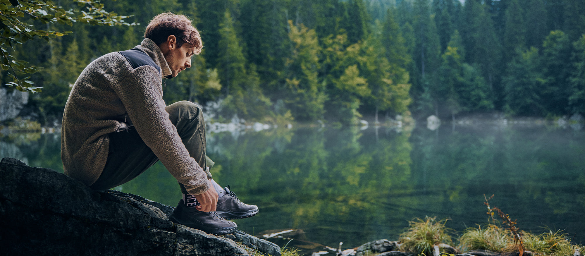 Hiker standing on a rocky outcrop in a forest with SCARPA's Rove Rock S GTX urban outdoor shoes.