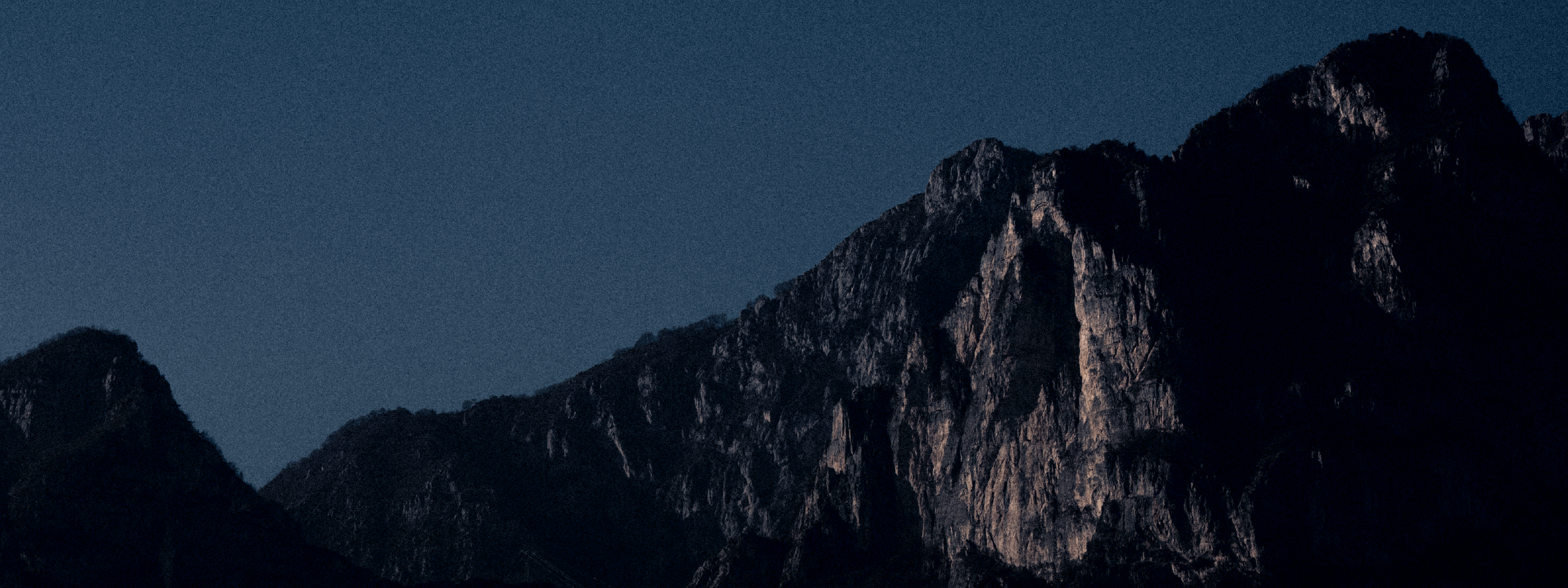 Panoramic view of an outdoor rock climbing wall at night.