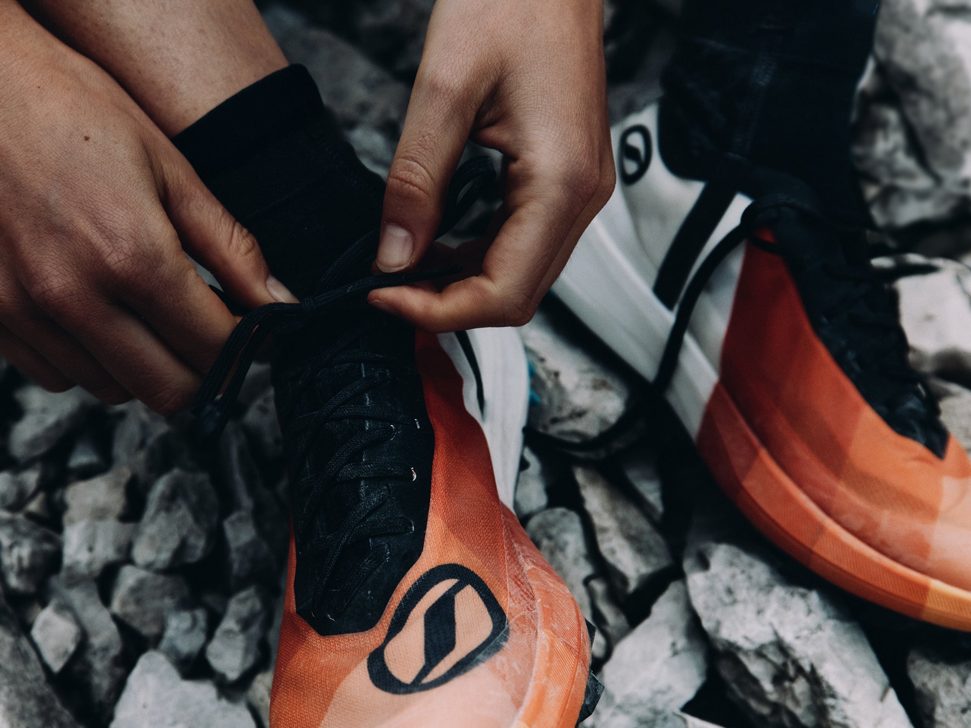 Close-up of a trail runner tying the laces of SCARPA's Alien Sky trail running shoes.