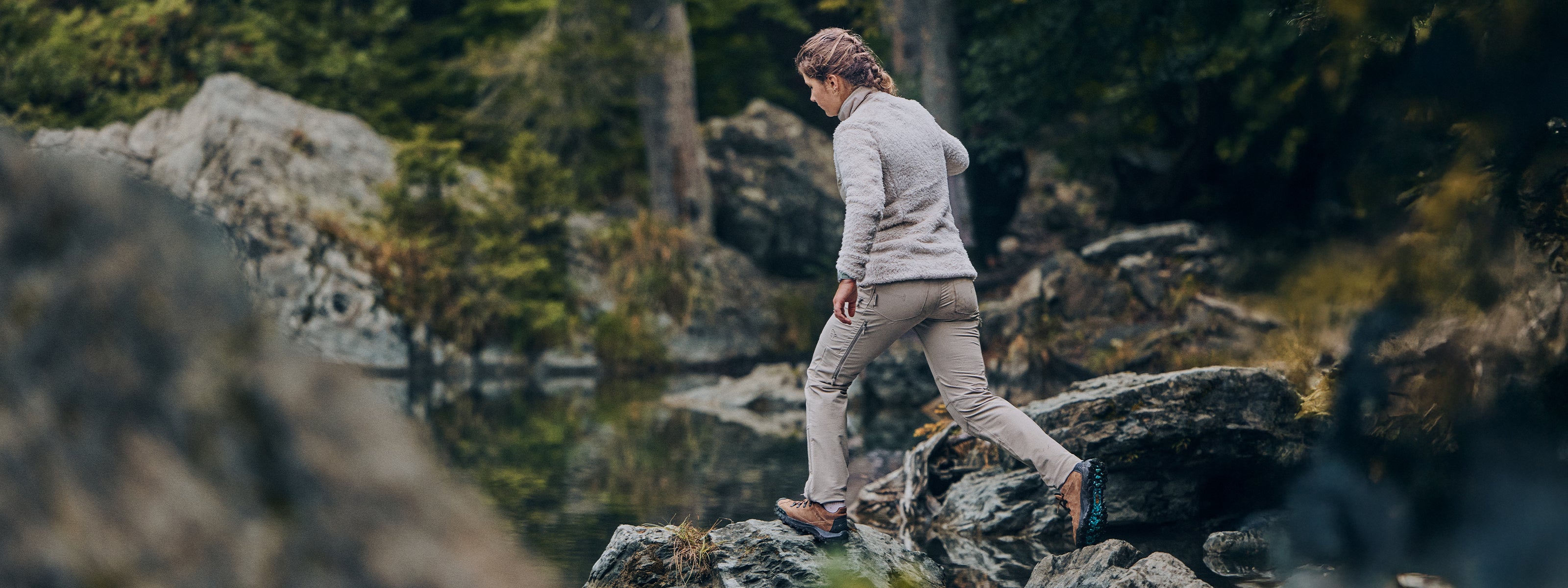 Person walking on rocks in a forest wearing SCARPA's ROVE ROCK S GTX urban outdoor shoes.