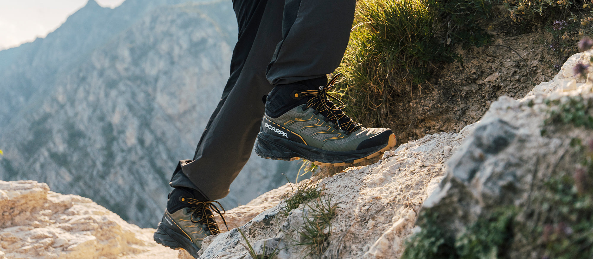 Hiker on a mountain trail wearing Rush 2 GTX MID