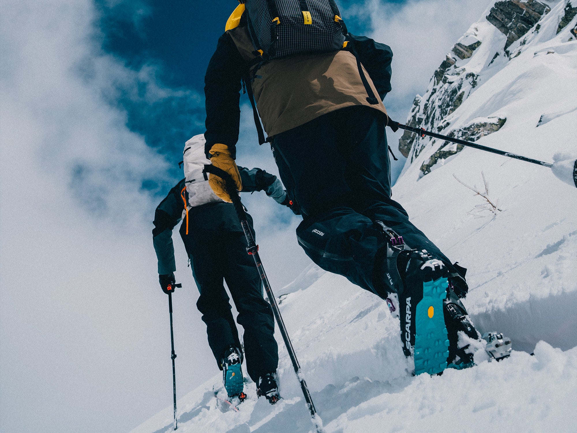 Two mountaineers ascending a snowy mountain ridge while wearing SCARPA's F1 XT ski mountaineering boots.
