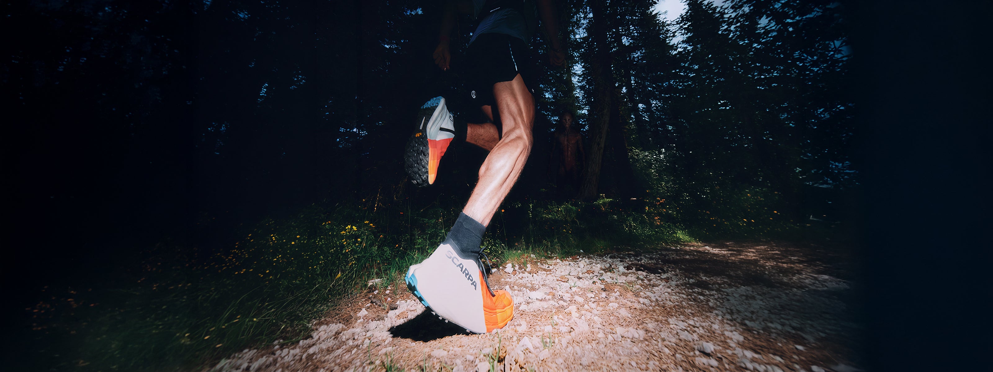 Trail runner on a forest path wearing SCARPA Alien Ultra trail running shoes.