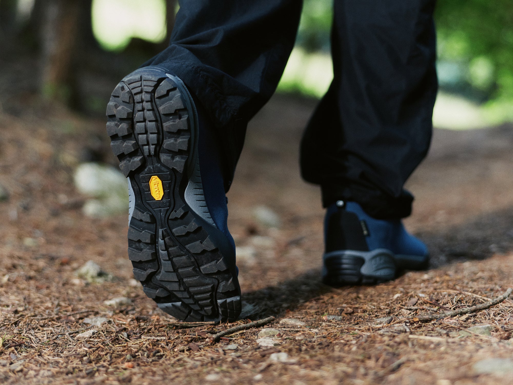 Close-up of a person walking on a forest path, showing the Vibram sole of pair of SCARPA Mojito GTX urban lifestyle shoes.