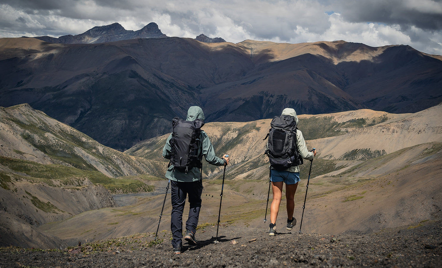 Hikers with backpacks and walking sticks standing on a mountain trail with SCARPA's trail shoes