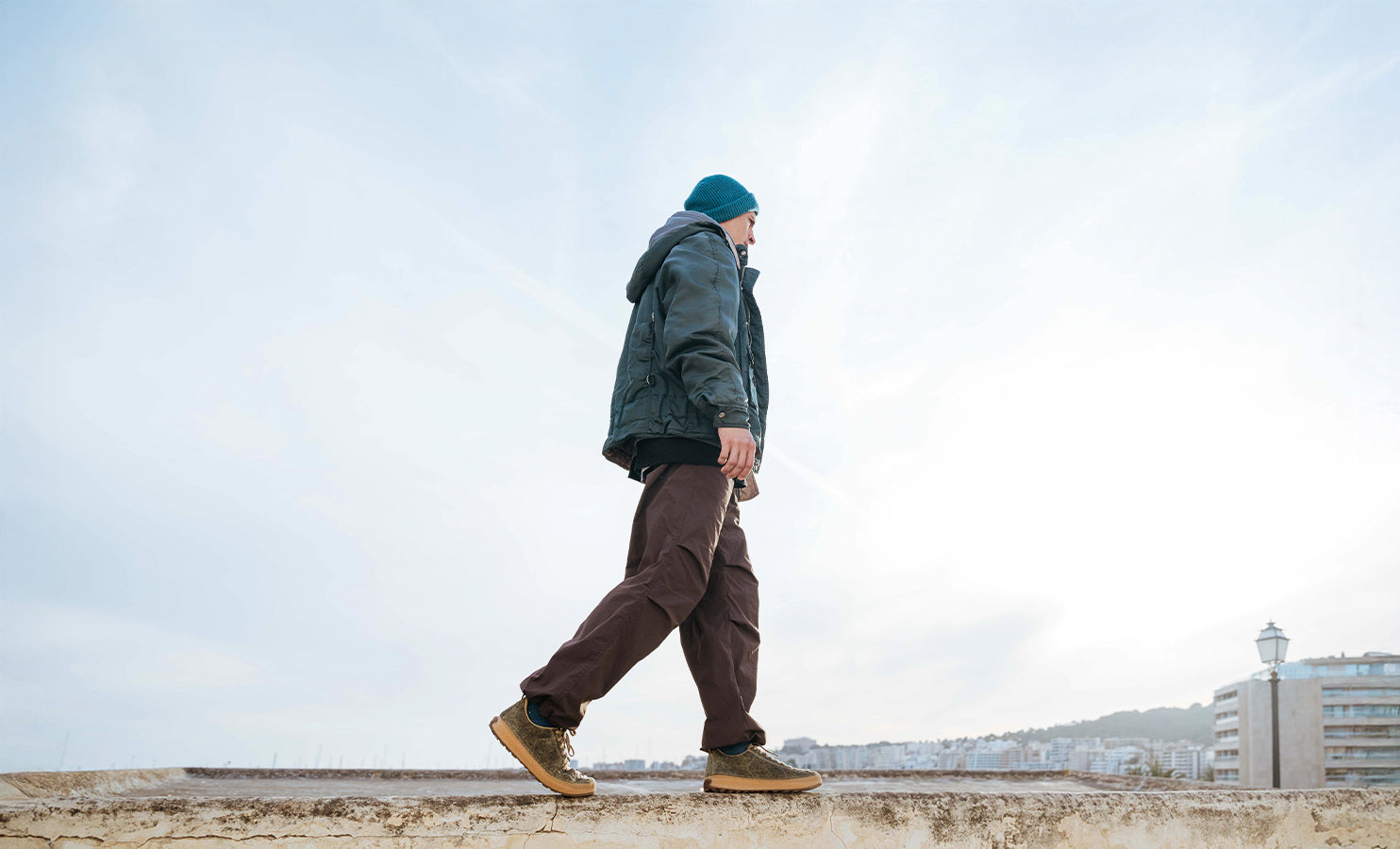 Person walking on a ledge with a clear sky background wearing SCARPA's urban outdoor shoes